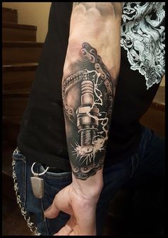 a man with a tattoo on his arm holding a wrench in one hand and chain around the other