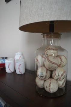 a glass jar filled with baseballs sitting on top of a table next to a lamp