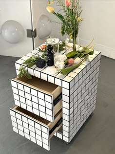 a table with flowers and other items on it in a room next to a wall