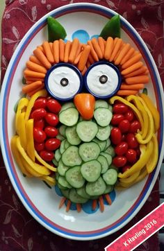 a plate that has some vegetables on it and an owl face made out of carrots