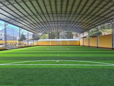 an indoor soccer field with green grass and white lines on the sidelines, surrounded by yellow walls