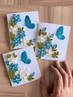 three handmade greeting cards with blue and white butterflies on them, one being held up by someone's hands