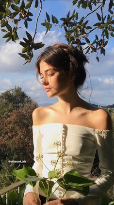 a woman in white dress standing next to a tree