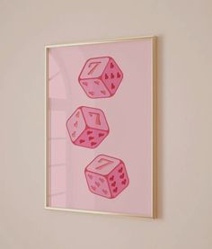 three pink dices are hanging on the wall in front of a white frame with gold trim