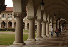 several people walking down a walkway between two large pillars