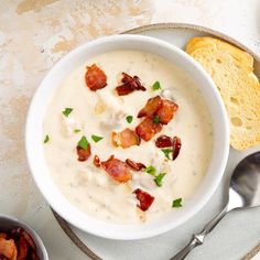 a bowl of soup with bacon and cheese in it on a plate next to bread