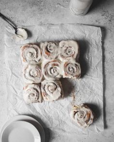 cinnamon rolls with icing sitting on top of a piece of paper