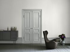 an empty room with a chair and vases on the floor in front of it