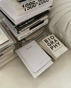 a stack of books sitting on top of a bed next to a white comforter