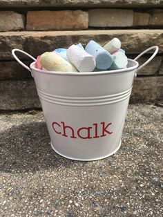 a bucket filled with chalk sitting on top of a stone floor next to a brick wall