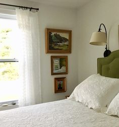 a bed with white sheets and pillows in a bedroom next to two pictures on the wall