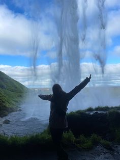 a woman standing in front of a geyser with her arms spread wide open