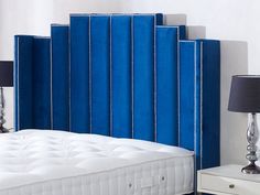 a blue headboard is next to a white bed with two lamps on either side