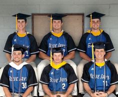 a group of young men sitting next to each other wearing graduation caps and gowns