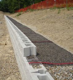 concrete blocks are placed on the side of a construction site, with red wires running through them