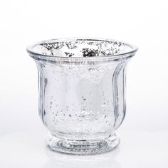 a clear glass vase with water droplets on the rim and bottom, sitting on a white surface