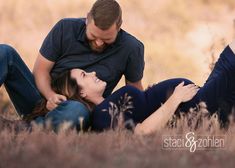 a man and woman laying on the ground in tall grass