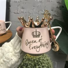 a person holding a pink coffee mug with gold crowns on it and the words queen of everything