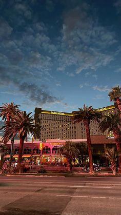 the las vegas hotel and casino is lit up at night with palm trees in front