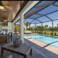 an outdoor swimming pool and covered patio area with table, chairs, and couches