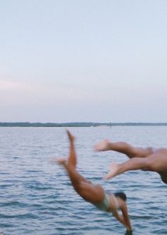 two people jumping into the water from a dock