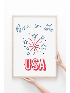 two hands holding up a framed poster with the words born in the usa written on it