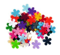 colorful felt flowers are scattered on a white surface