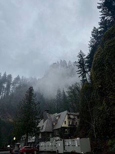 a large house sitting on the side of a road in front of some tall trees