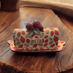 a strawberry themed butter container sitting on top of a wooden table