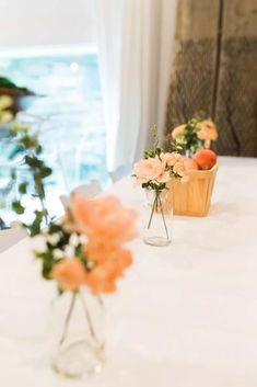 three vases filled with flowers sitting on top of a white tablecloth covered table