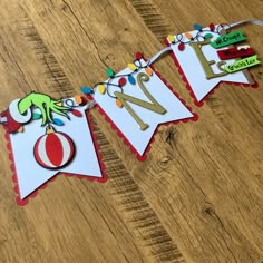 a paper banner with the letter n on it is hanging from a wooden floor and decorated with christmas lights