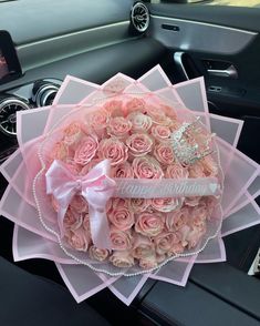 a bouquet of pink roses in the center of a car dashboard with a tiara on top