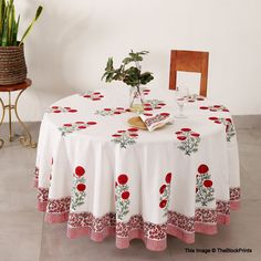 a white table with red flowers on it and a potted plant next to it