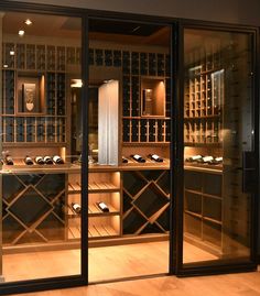 a room filled with lots of bottles of wine and glass doors that lead into the cellar