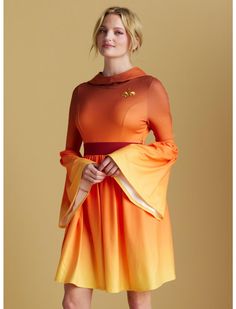 a woman in an orange and yellow dress posing for the camera with her hands on her hips