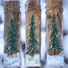 three pieces of wood with trees painted on them in the snow, tied together and sitting next to each other