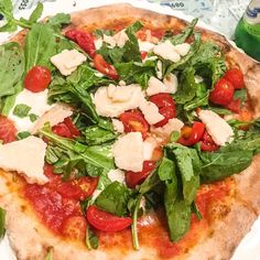 a pizza with spinach, tomatoes and cheese on it