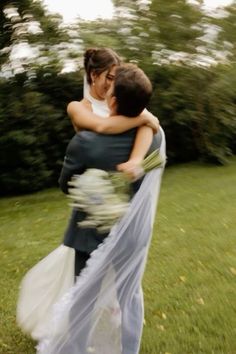 two people hugging each other in the grass