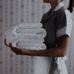 a woman holding stack of white towels in her hands