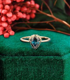 a close up of a ring on top of a green box with flowers in the background