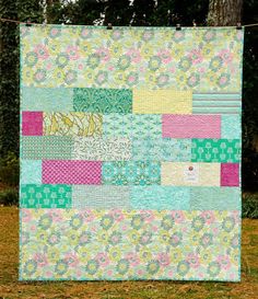 a quilt hanging on a clothes line in front of some trees and grass with the words,