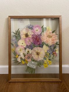 a vase filled with lots of flowers sitting on top of a wooden table next to a wall