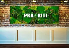 a brick wall with the words prakriti on it in front of a green plant