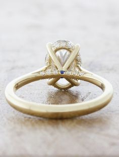 a yellow gold engagement ring with an oval cut diamond in the center and side stones