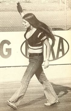 a woman walking across a tennis court holding a racquet in her right hand