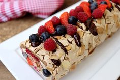 a white plate topped with a piece of cake covered in fruit