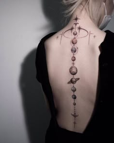 the back of a woman's neck with planets and stars on it