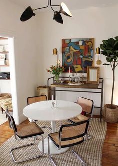 a white table and chairs in a room with wooden floors, artwork on the wall