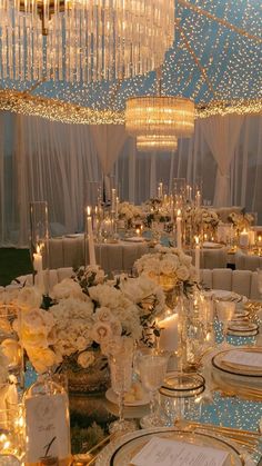 a table set up for a formal dinner with candles, flowers and place settings on it