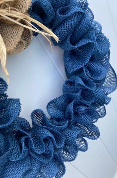 a blue wreath with burlap and straw on it sitting on a white surface